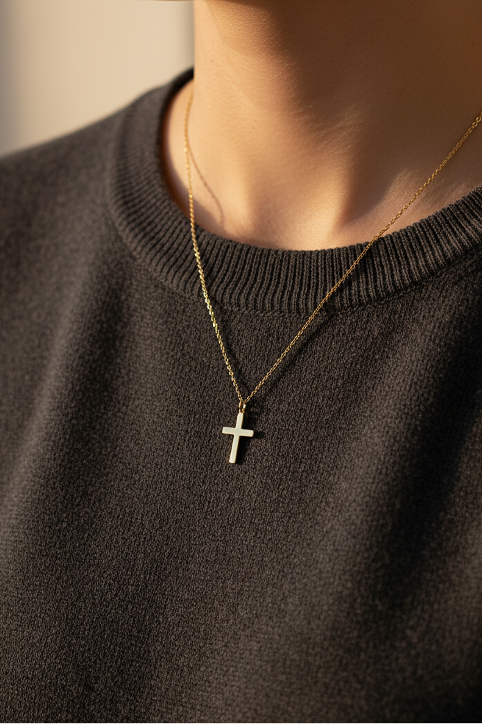 Collier croix doré sur chandail foncé
